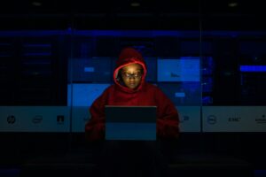 A woman sitting in the dark looking at a laptop screen
