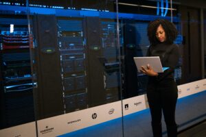 Female engineer with a laptop standing in front of a rack of servers