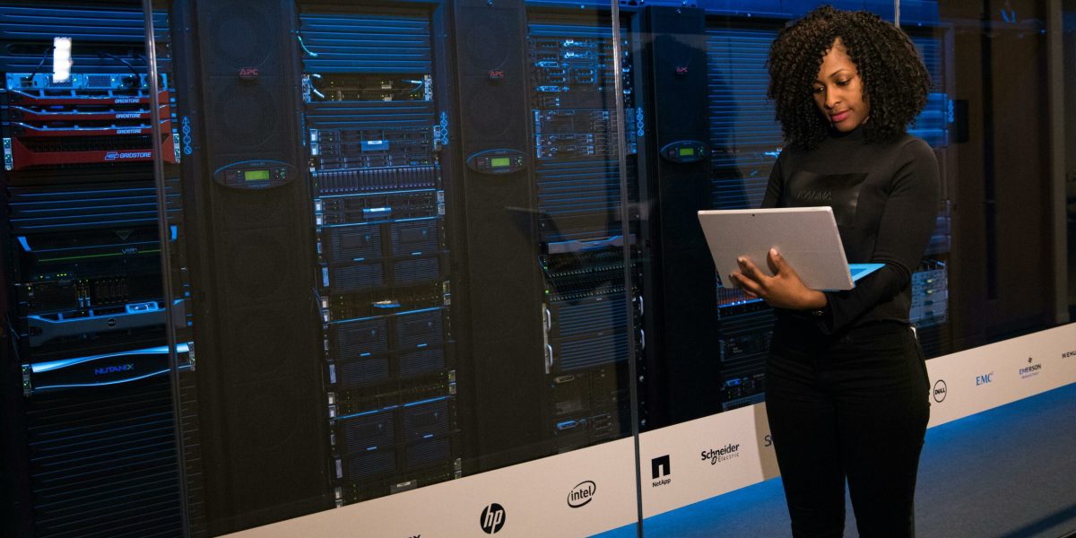 Female engineer with a laptop standing in front of a rack of servers